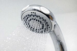 Vettä säästävä suihkupää käytössä, josta vesi virtaa tasaisina noroina.