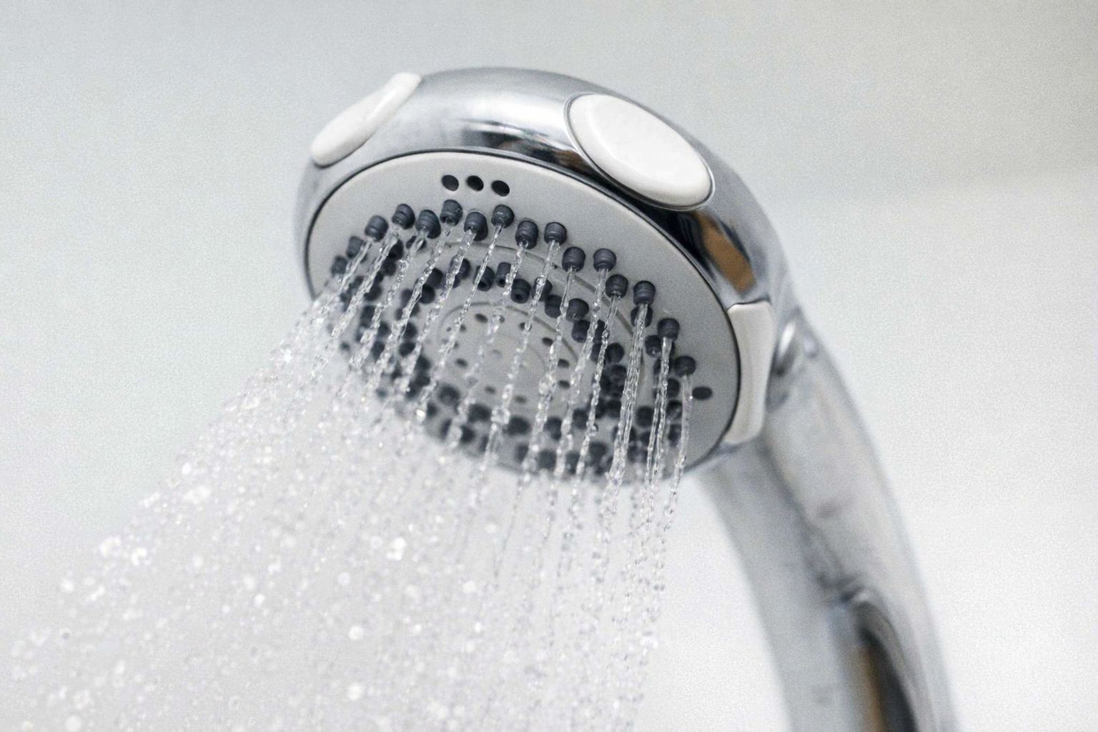 Vettä säästävä suihkupää käytössä, josta vesi virtaa tasaisina noroina.